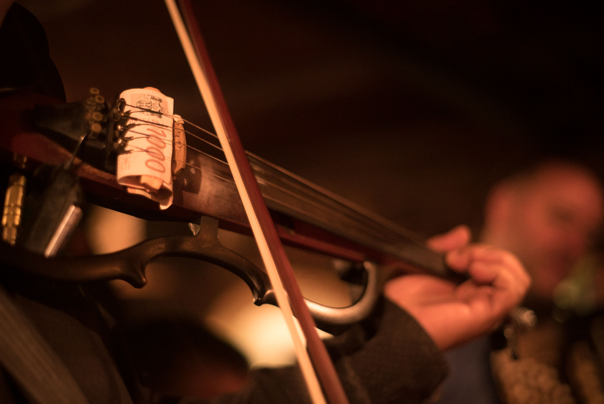 it's customary to sneak up to the musicians from behind to stick a tip somewhere in their instrument while causing as little distraction as possible